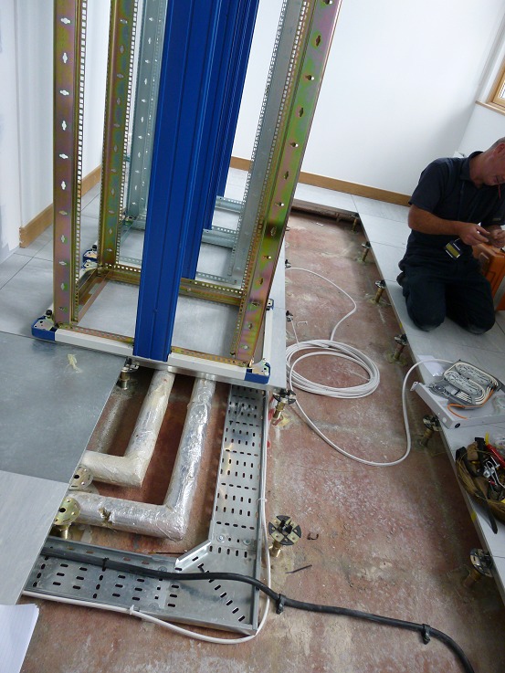 First rack frame going up over a floor void that was never designed to carry a comms room