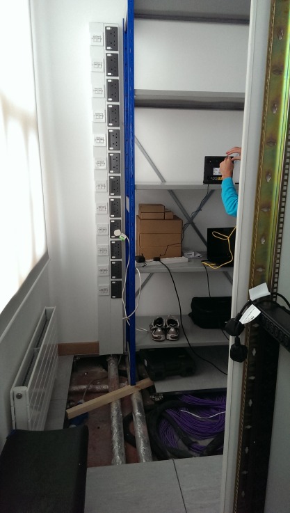 Dado-fed PDU strip running floor-to-ceiling alongside the shelving