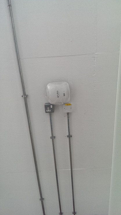 One of three Aruba access points, ceiling-mounted with power and data alongside